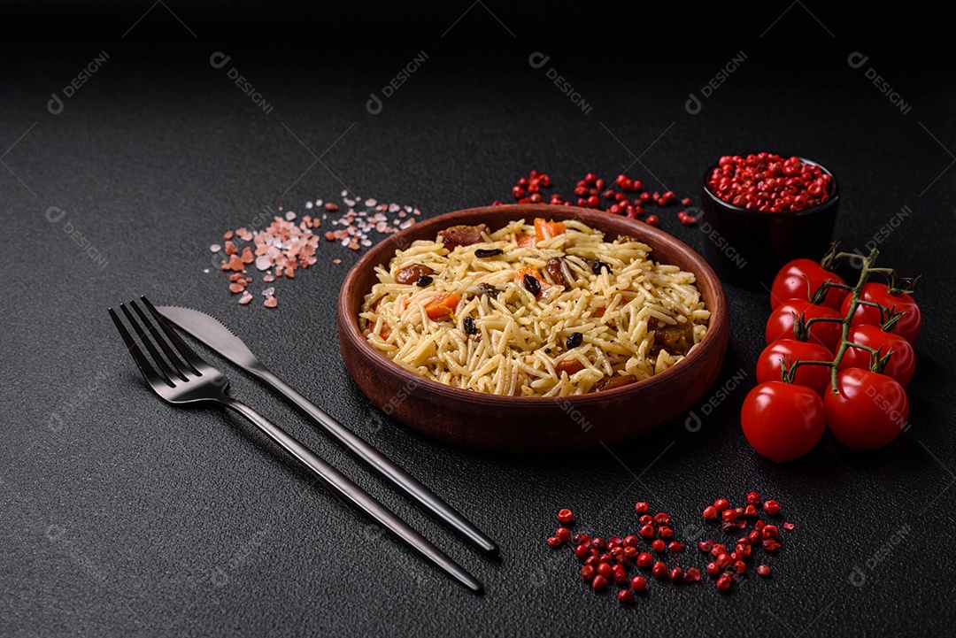 Delicioso pilaf uzbeque com frango, cenoura, bérberis, especiarias e ervas sobre um fundo escuro de concreto