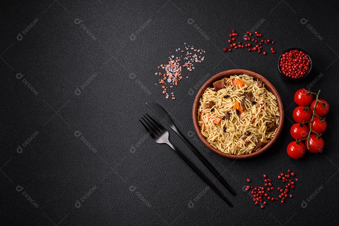 Delicioso pilaf uzbeque com frango, cenoura, bérberis, especiarias e ervas sobre um fundo escuro de concreto