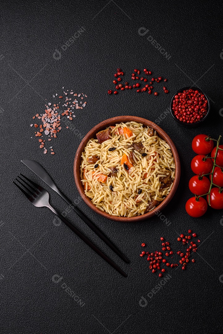 Delicioso pilaf uzbeque com frango, cenoura, bérberis, especiarias e ervas sobre um fundo escuro de concreto