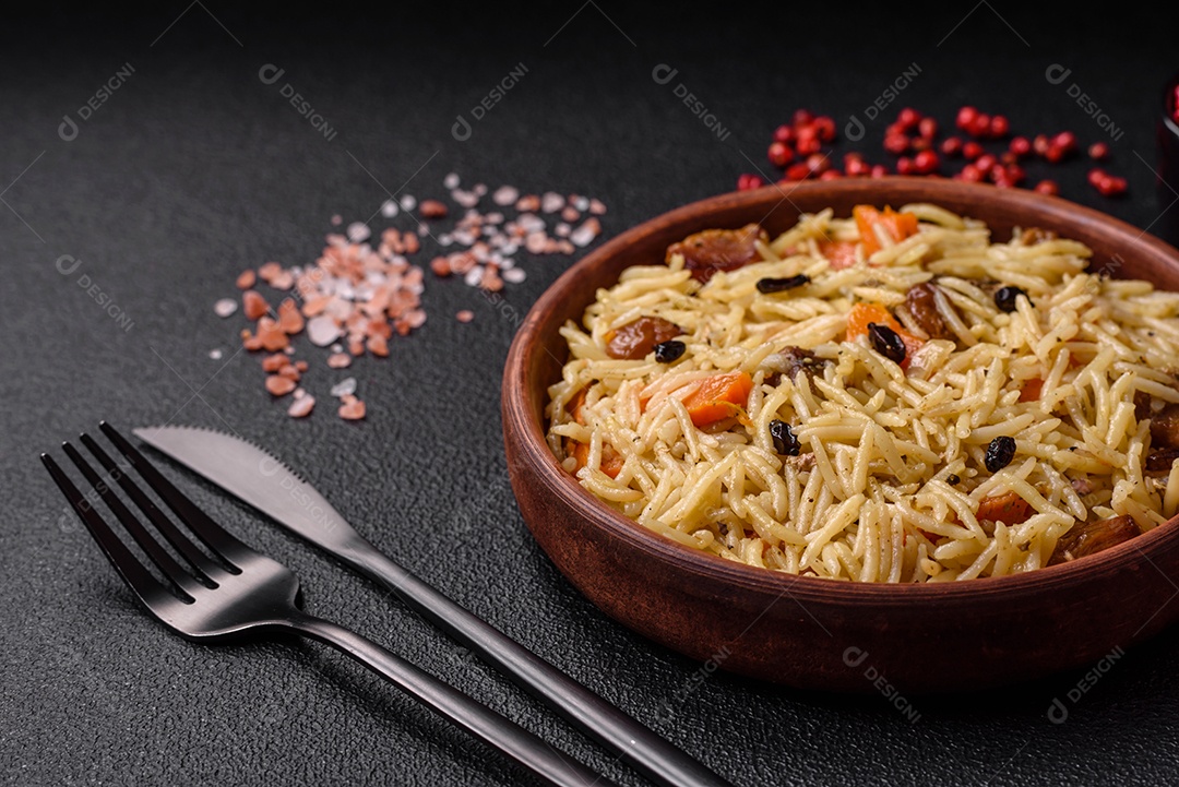 Delicioso pilaf uzbeque com frango, cenoura, bérberis, especiarias e ervas sobre um fundo escuro de concreto