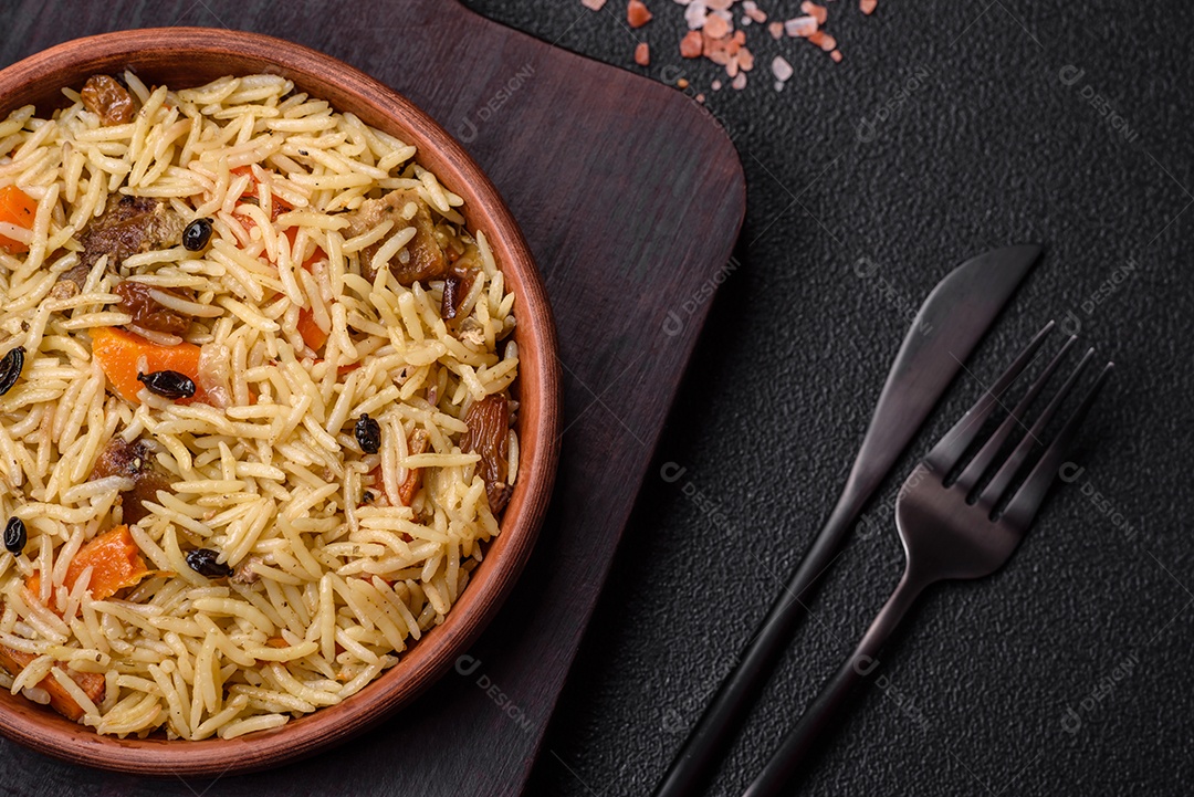 Delicioso pilaf uzbeque com frango, cenoura, bérberis, especiarias e ervas sobre um fundo escuro de concreto