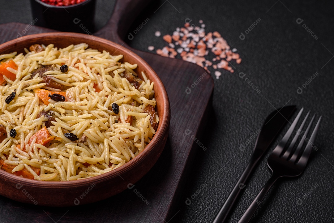 Delicioso pilaf uzbeque com frango, cenoura, bérberis, especiarias e ervas sobre um fundo escuro de concreto