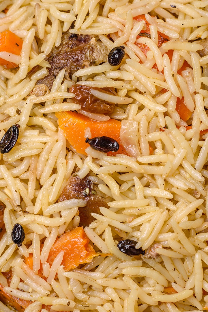Delicioso pilaf uzbeque com frango, cenoura, bérberis, especiarias e ervas sobre um fundo escuro de concreto