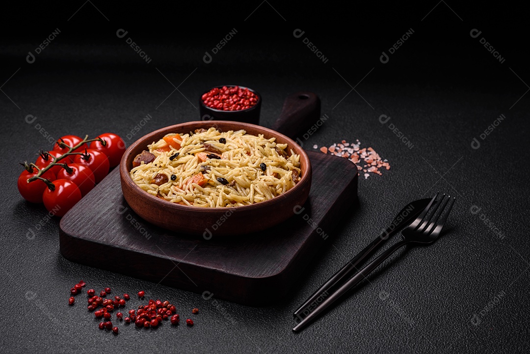 Delicioso pilaf uzbeque com frango, cenoura, bérberis, especiarias e ervas sobre um fundo escuro de concreto