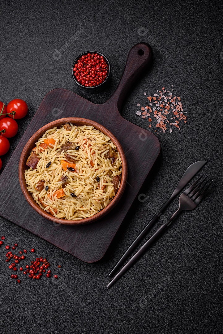 Delicioso pilaf uzbeque com frango, cenoura, bérberis, especiarias e ervas sobre um fundo escuro de concreto