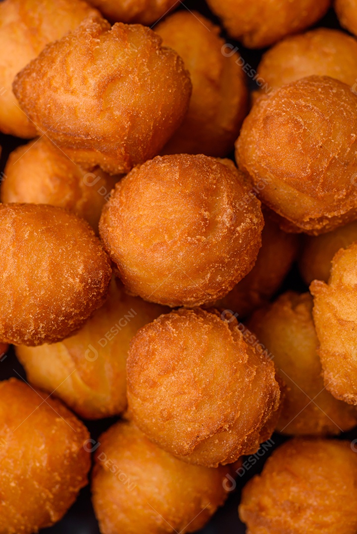 Deliciosas bolas de batata frita com mussarela à milanesa, sal, especiarias e ervas sobre um fundo escuro de concreto