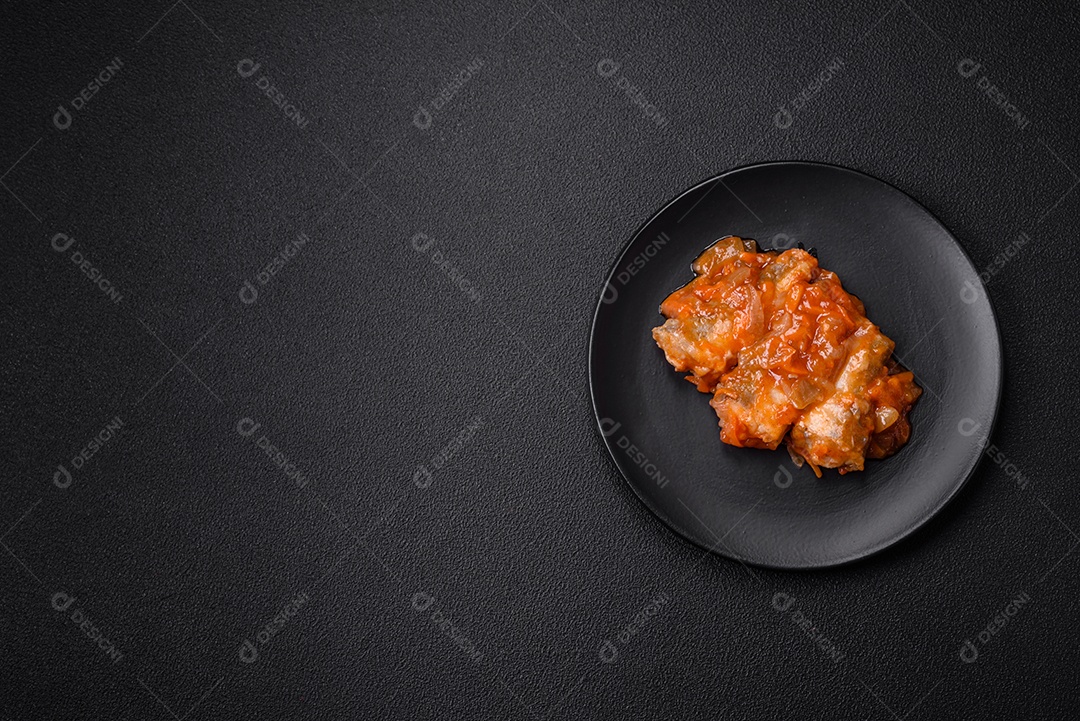 Delicioso guisado fresco de batatas, tomates, cebolas, cenouras e carne bovina com sal, especiarias e ervas sobre um fundo escuro de concreto