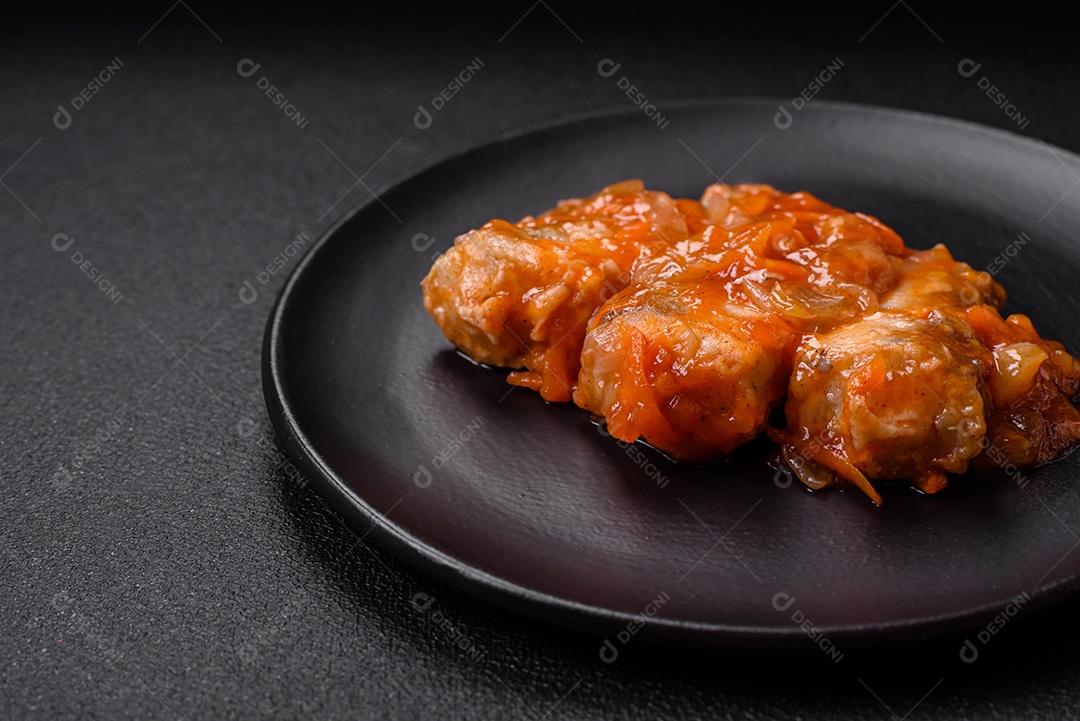 Delicioso guisado fresco de batatas, tomates, cebolas, cenouras e carne bovina com sal, especiarias e ervas sobre um fundo escuro de concreto