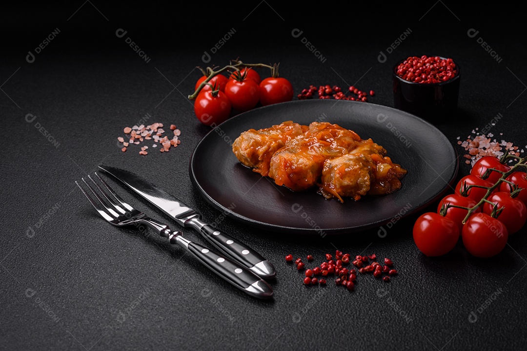 Delicioso guisado fresco de batatas, tomates, cebolas, cenouras e carne bovina com sal, especiarias e ervas sobre um fundo escuro de concreto