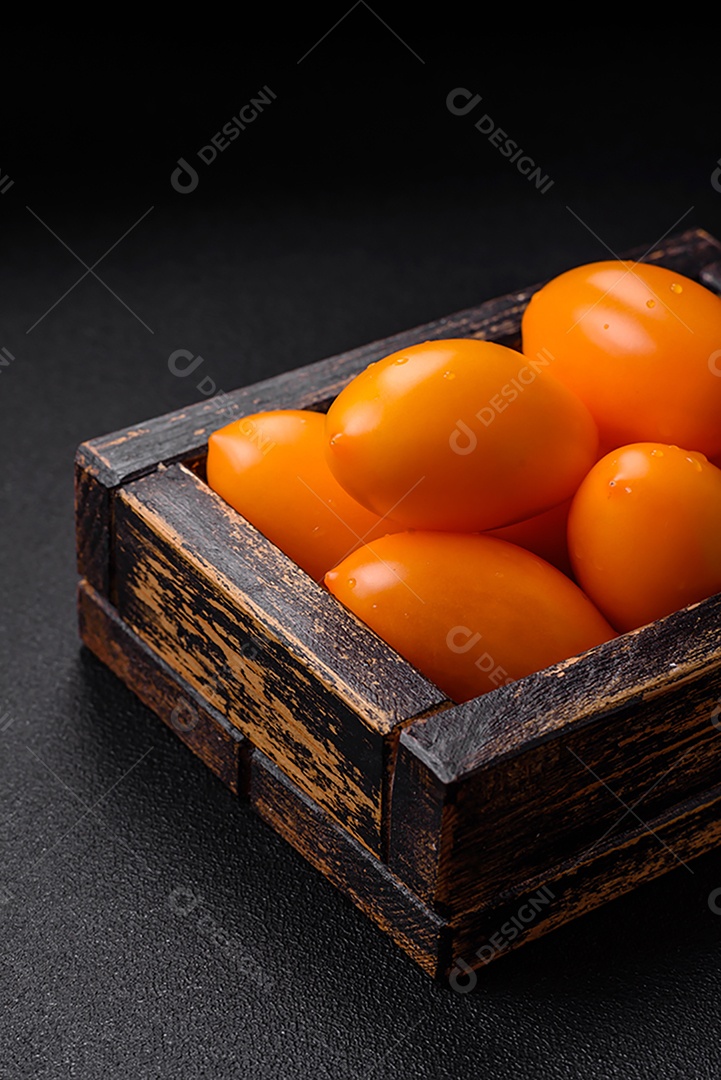 Tomates amarelos frescos e brilhantes em forma de ameixa sobre um fundo de concreto texturizado preto