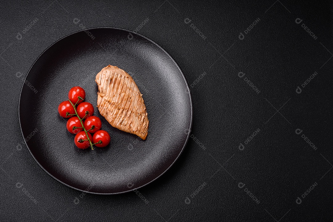 Delicioso suculento filé de frango grelhado com sal, especiarias e ervas sobre um fundo escuro de concreto