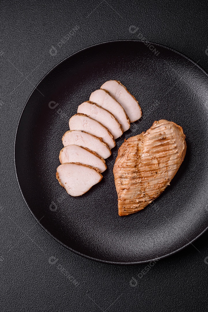 Delicioso suculento filé de frango grelhado com sal, especiarias e ervas sobre um fundo escuro de concreto