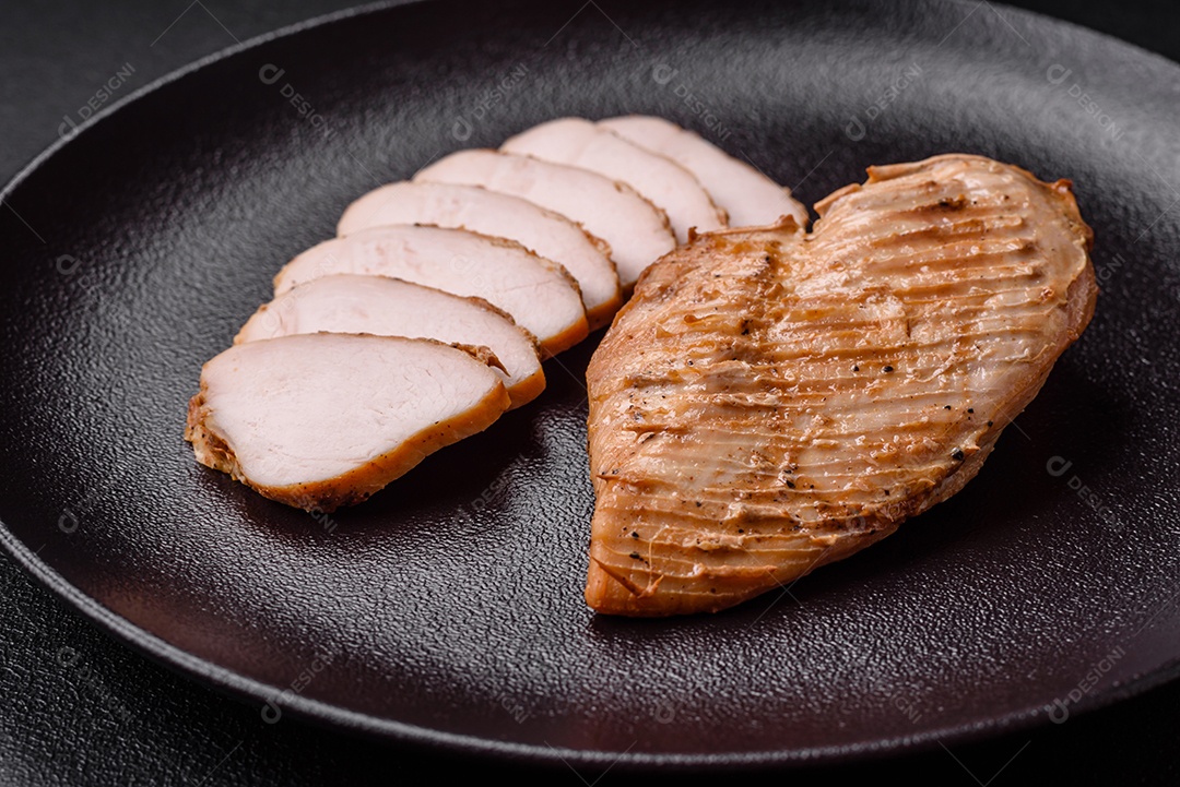 Delicioso suculento filé de frango grelhado com sal, especiarias e ervas sobre um fundo escuro de concreto