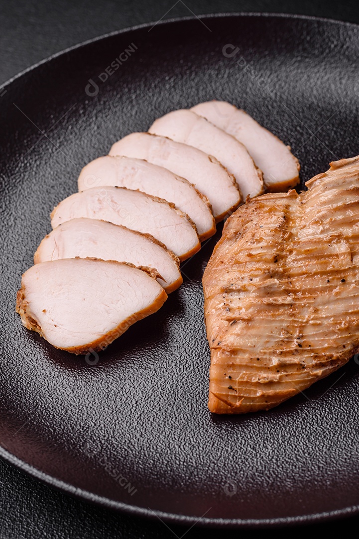 Delicioso suculento filé de frango grelhado com sal, especiarias e ervas sobre um fundo escuro de concreto