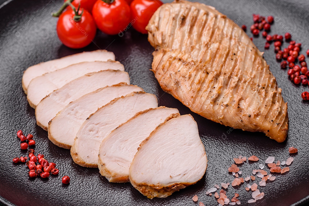 Delicioso suculento filé de frango grelhado com sal, especiarias e ervas sobre um fundo escuro de concreto