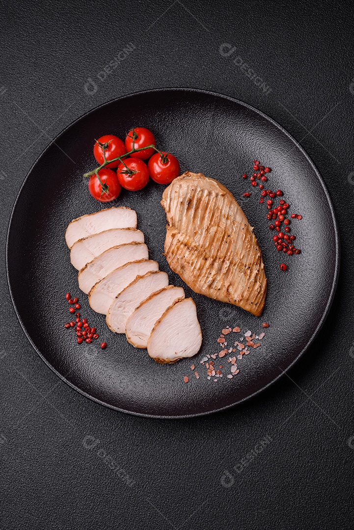 Delicioso suculento filé de frango grelhado com sal, especiarias e ervas sobre um fundo escuro de concreto