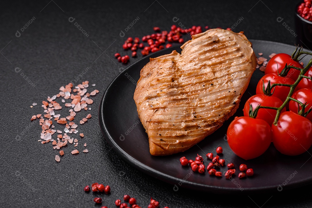 Delicioso suculento filé de frango grelhado com sal, especiarias e ervas sobre um fundo escuro de concreto