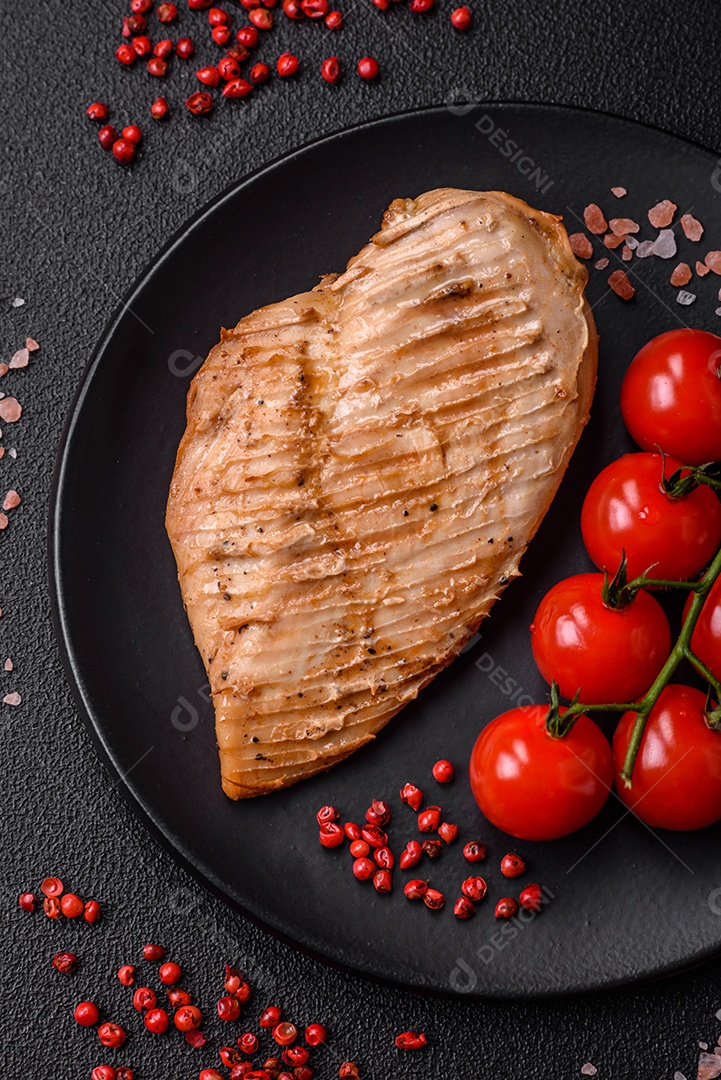 Delicioso suculento filé de frango grelhado com sal, especiarias e ervas sobre um fundo escuro de concreto