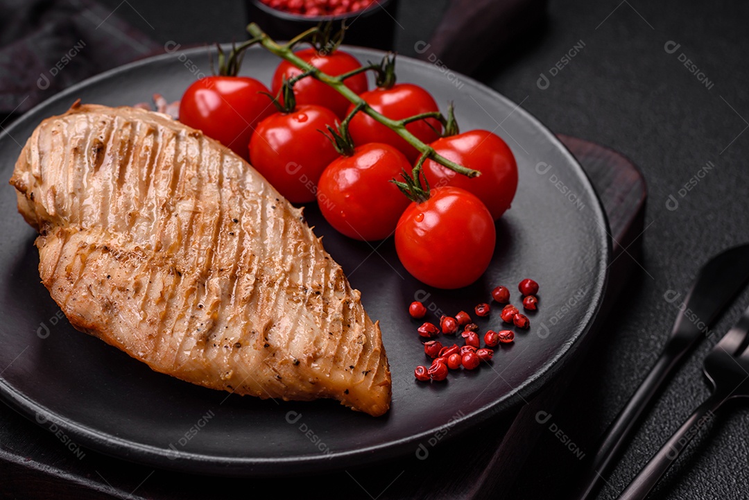 Delicioso suculento filé de frango grelhado com sal, especiarias e ervas sobre um fundo escuro de concreto