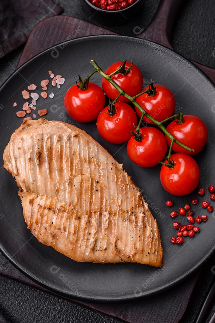 Delicioso suculento filé de frango grelhado com sal, especiarias e ervas sobre um fundo escuro de concreto