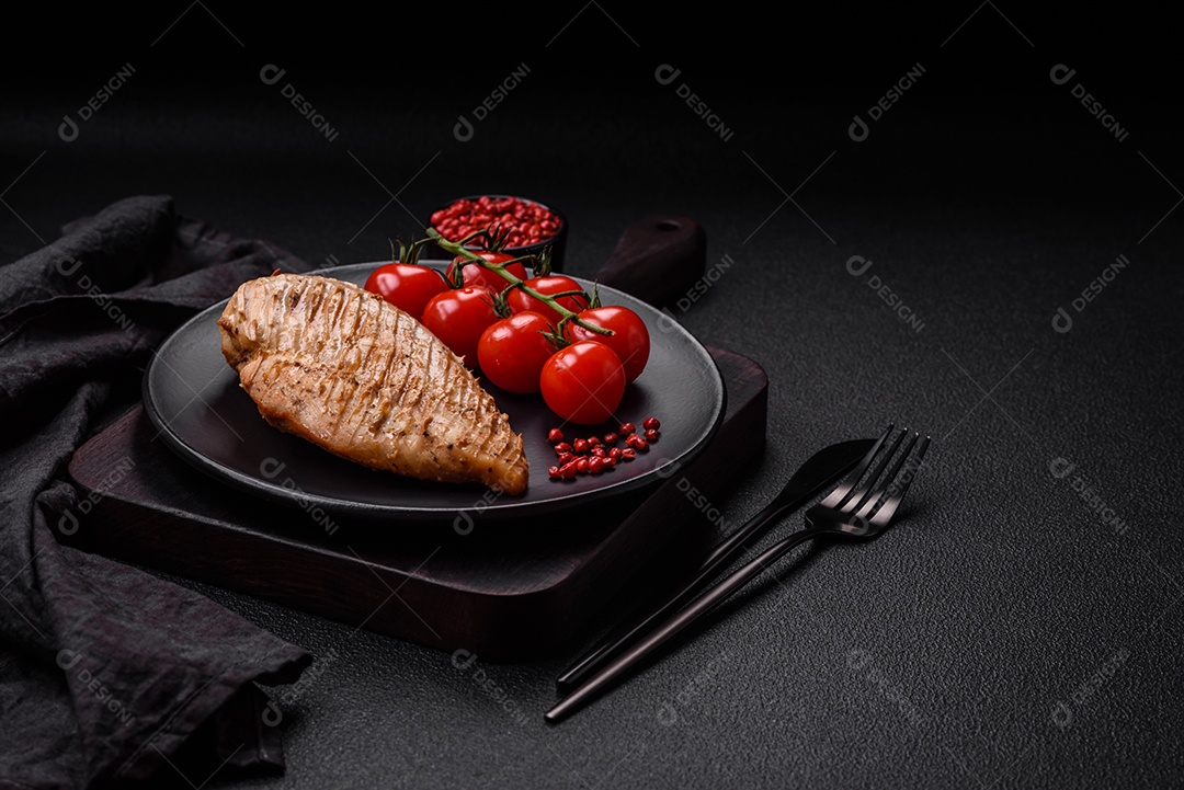 Delicioso suculento filé de frango grelhado com sal, especiarias e ervas sobre um fundo escuro de concreto