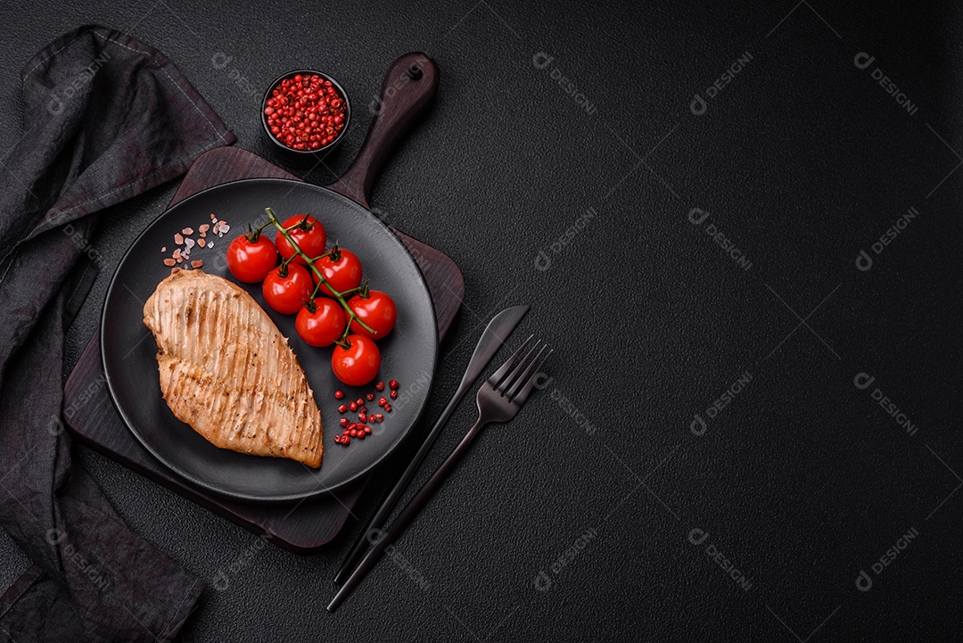 Delicioso suculento filé de frango grelhado com sal, especiarias e ervas sobre um fundo escuro de concreto