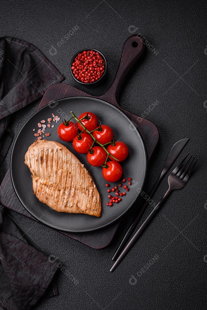Delicioso suculento filé de frango grelhado com sal, especiarias e ervas sobre um fundo escuro de concreto
