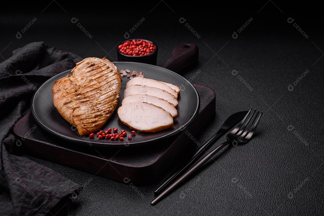 Delicioso suculento filé de frango grelhado com sal, especiarias e ervas sobre um fundo escuro de concreto