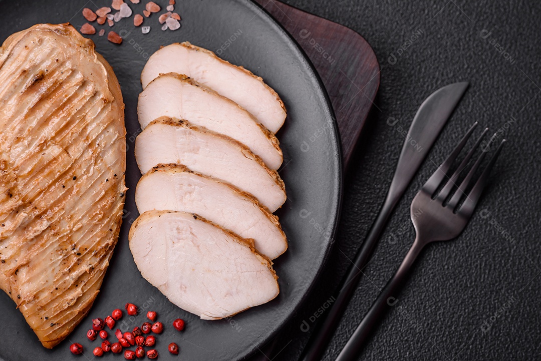 Delicioso suculento filé de frango grelhado com sal, especiarias e ervas sobre um fundo escuro de concreto