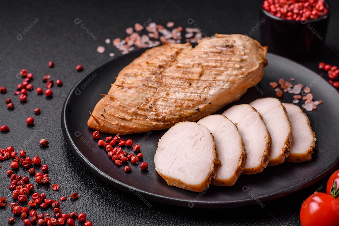 Delicioso suculento filé de frango grelhado com sal, especiarias e ervas sobre um fundo escuro de concreto