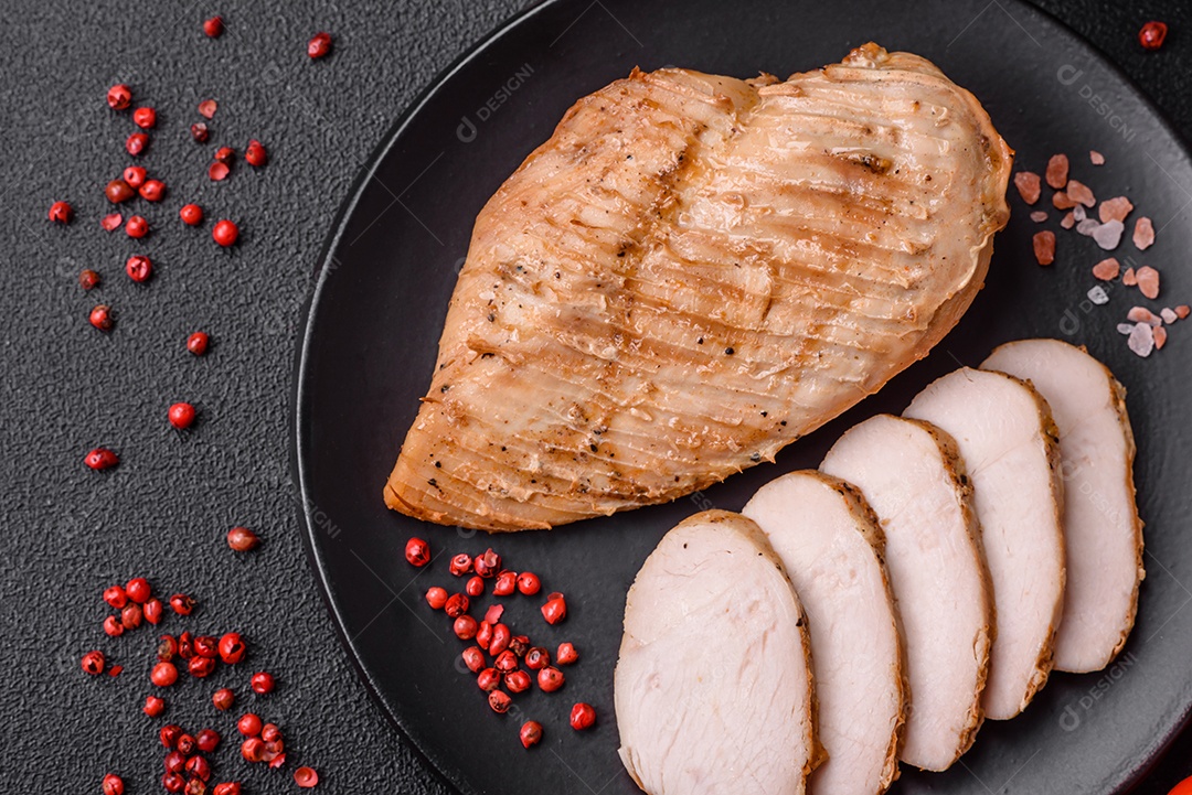 Delicioso suculento filé de frango grelhado com sal, especiarias e ervas sobre um fundo escuro de concreto