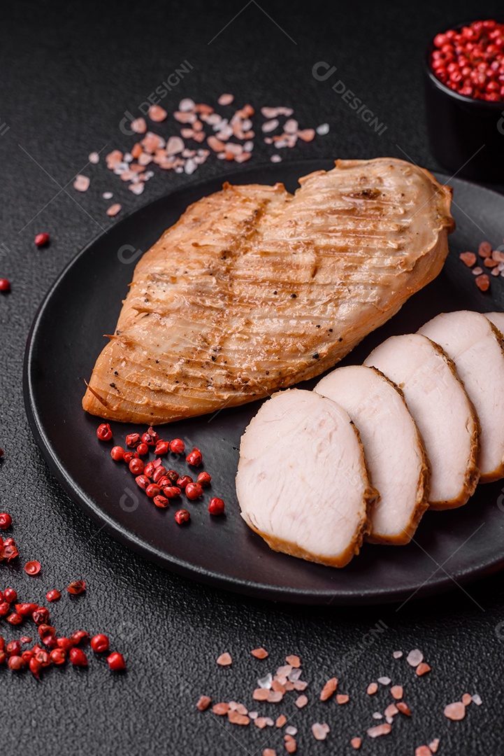 Delicioso suculento filé de frango grelhado com sal, especiarias e ervas sobre um fundo escuro de concreto