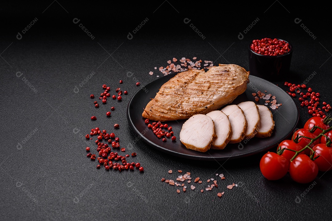 Delicioso suculento filé de frango grelhado com sal, especiarias e ervas sobre um fundo escuro de concreto