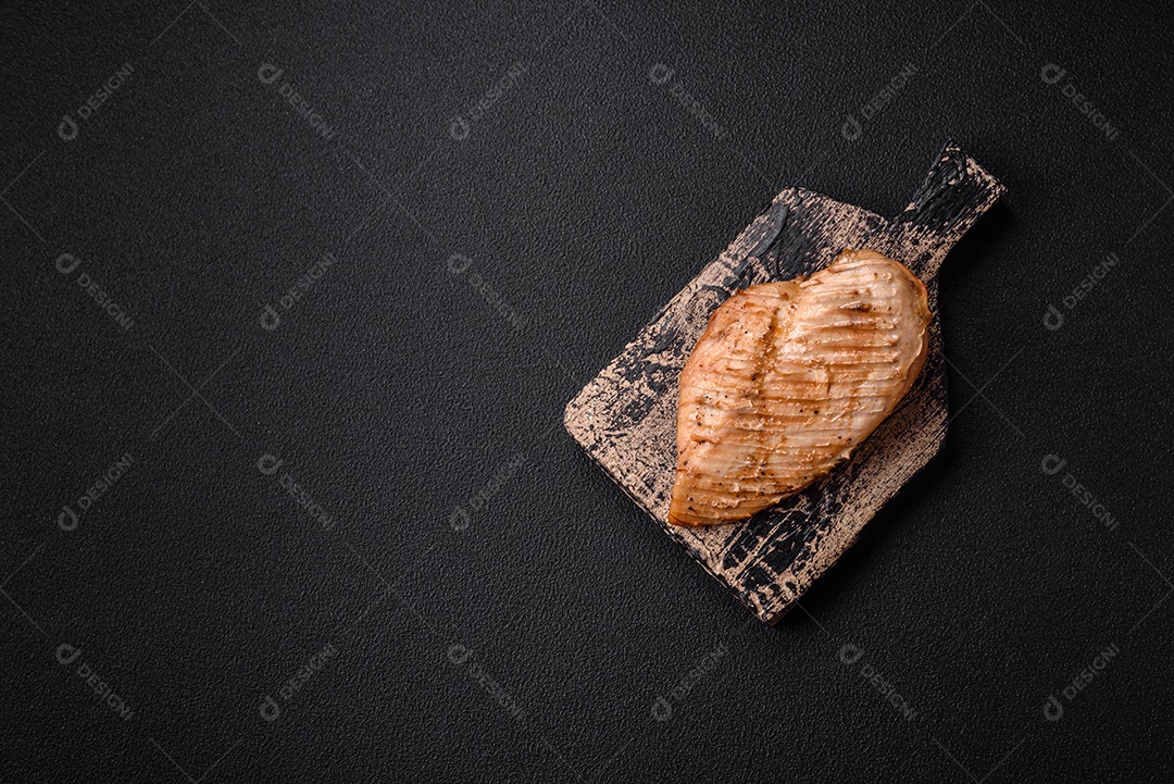 Delicioso suculento filé de frango grelhado com sal, especiarias e ervas sobre um fundo escuro de concreto