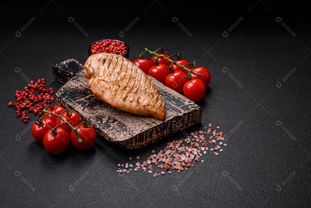 Delicioso suculento filé de frango grelhado com sal, especiarias e ervas sobre um fundo escuro de concreto