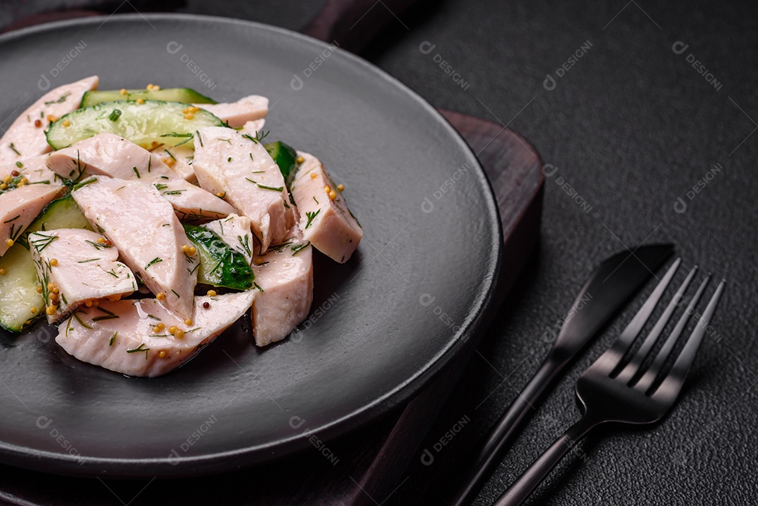 Deliciosa salada fresca e suculenta de pepino e fatias de frango grelhado, com mostarda francesa, sal e especiarias sobre um fundo escuro de concreto