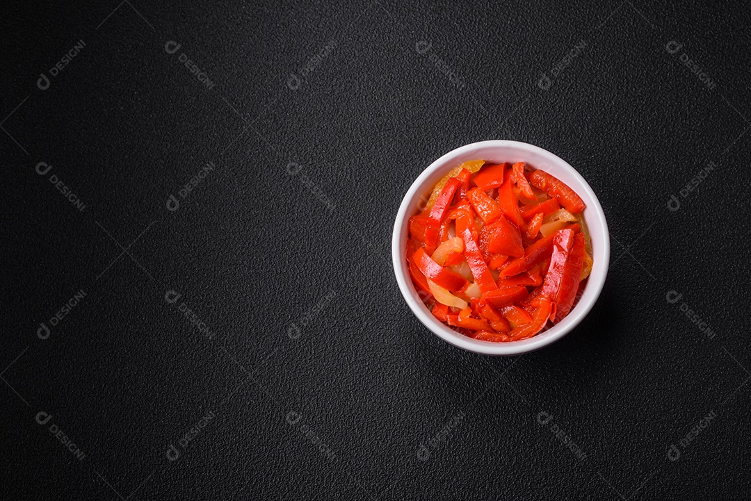 Deliciosas fatias frescas de pimentão doce com cebola, sal, especiarias e ervas sobre um fundo escuro de concreto