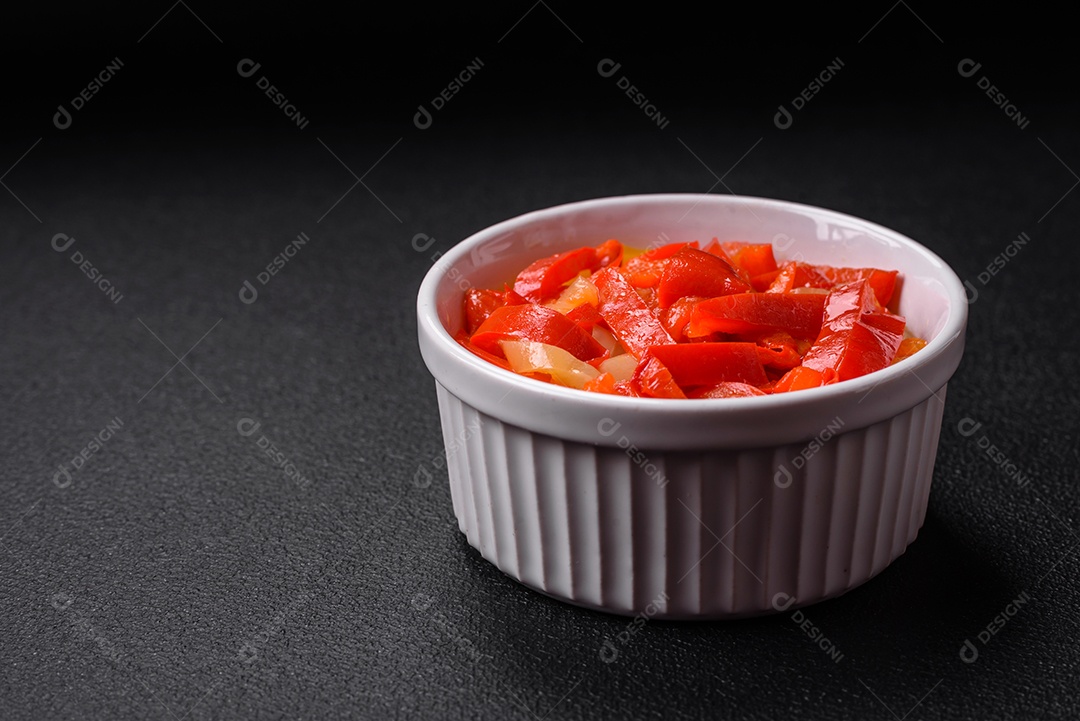 Deliciosas fatias frescas de pimentão doce com cebola, sal, especiarias e ervas sobre um fundo escuro de concreto