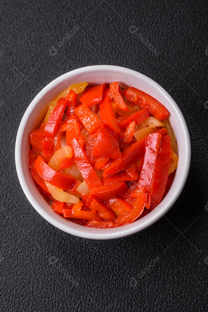 Deliciosas fatias frescas de pimentão doce com cebola, sal, especiarias e ervas sobre um fundo escuro de concreto