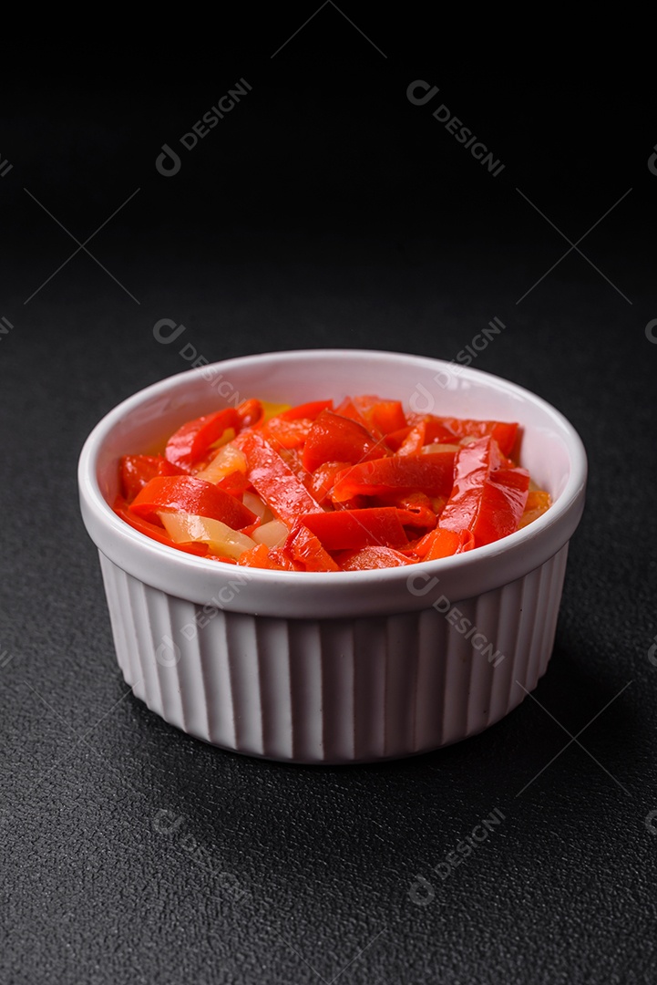 Deliciosas fatias frescas de pimentão doce com cebola, sal, especiarias e ervas sobre um fundo escuro de concreto