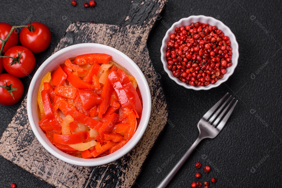 Deliciosas fatias frescas de pimentão doce com cebola, sal, especiarias e ervas sobre um fundo escuro de concreto