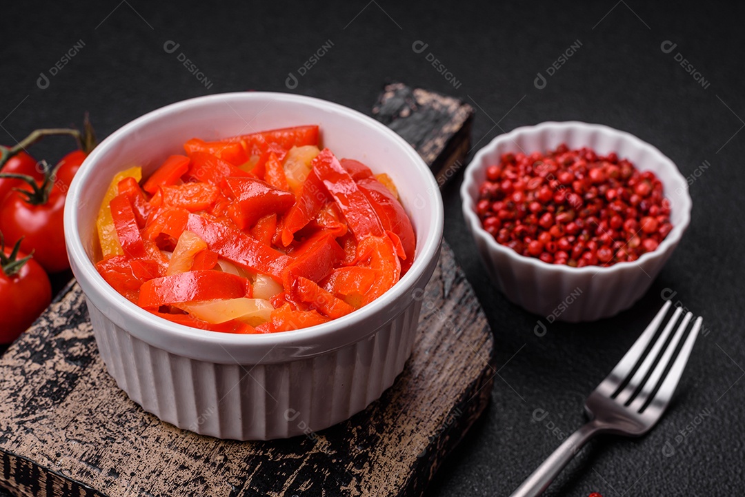 Deliciosas fatias frescas de pimentão doce com cebola, sal, especiarias e ervas sobre um fundo escuro de concreto