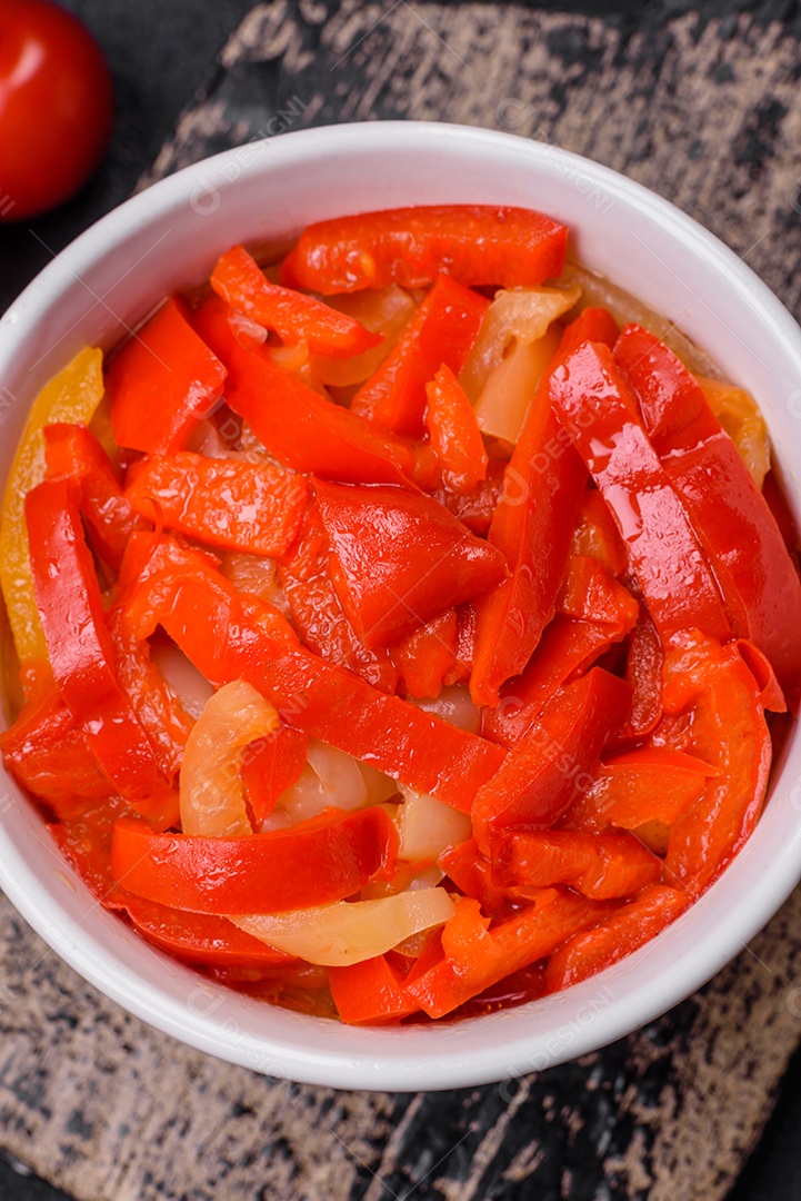 Deliciosas fatias frescas de pimentão doce com cebola, sal, especiarias e ervas sobre um fundo escuro de concreto