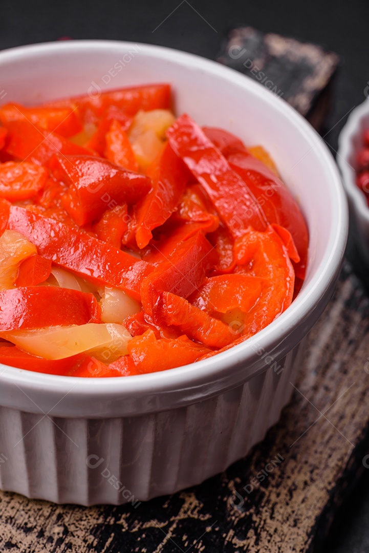 Deliciosas fatias frescas de pimentão doce com cebola, sal, especiarias e ervas sobre um fundo escuro de concreto
