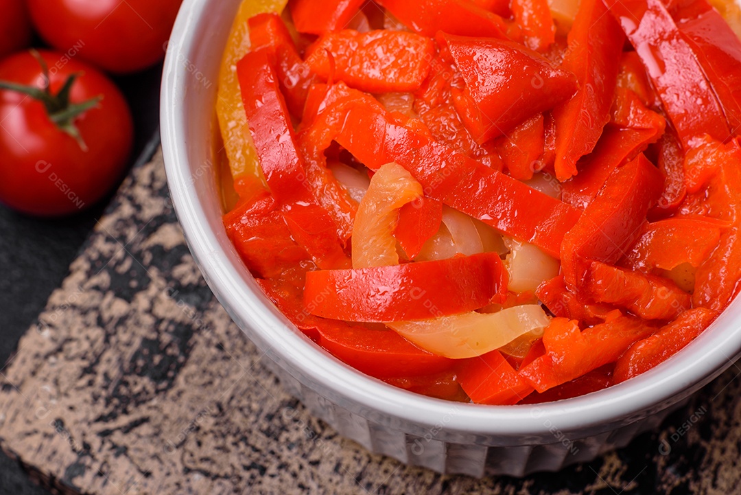 Deliciosas fatias frescas de pimentão doce com cebola, sal, especiarias e ervas sobre um fundo escuro de concreto