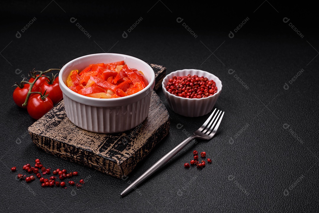 Deliciosas fatias frescas de pimentão doce com cebola, sal, especiarias e ervas sobre um fundo escuro de concreto