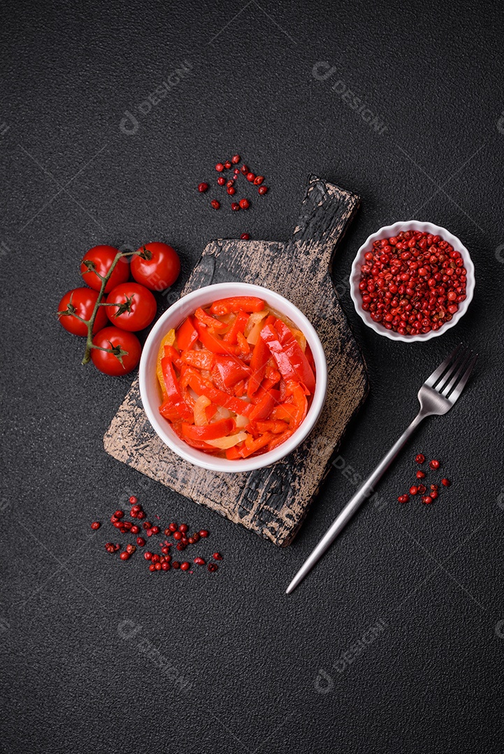 Deliciosas fatias frescas de pimentão doce com cebola, sal, especiarias e ervas sobre um fundo escuro de concreto