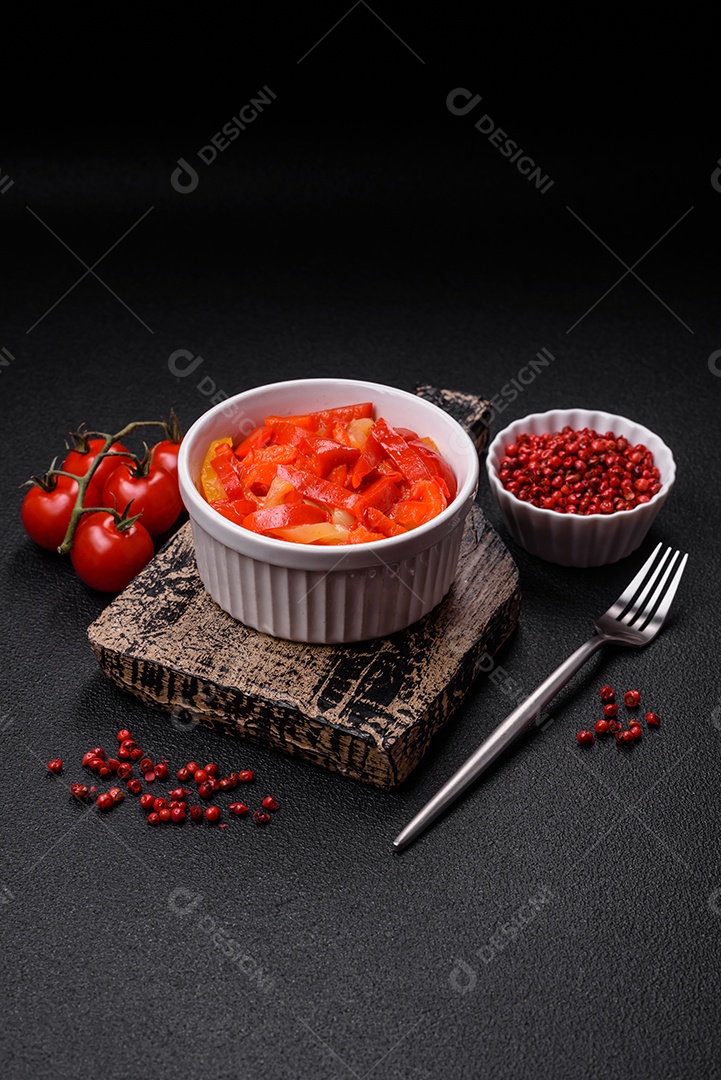 Deliciosas fatias frescas de pimentão doce com cebola, sal, especiarias e ervas sobre um fundo escuro de concreto