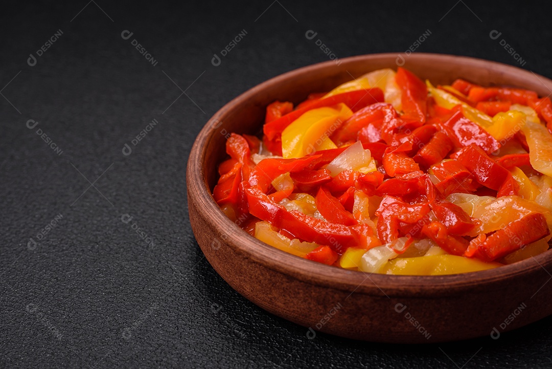 Deliciosas fatias frescas de pimentão doce com cebola, sal, especiarias e ervas sobre um fundo escuro de concreto