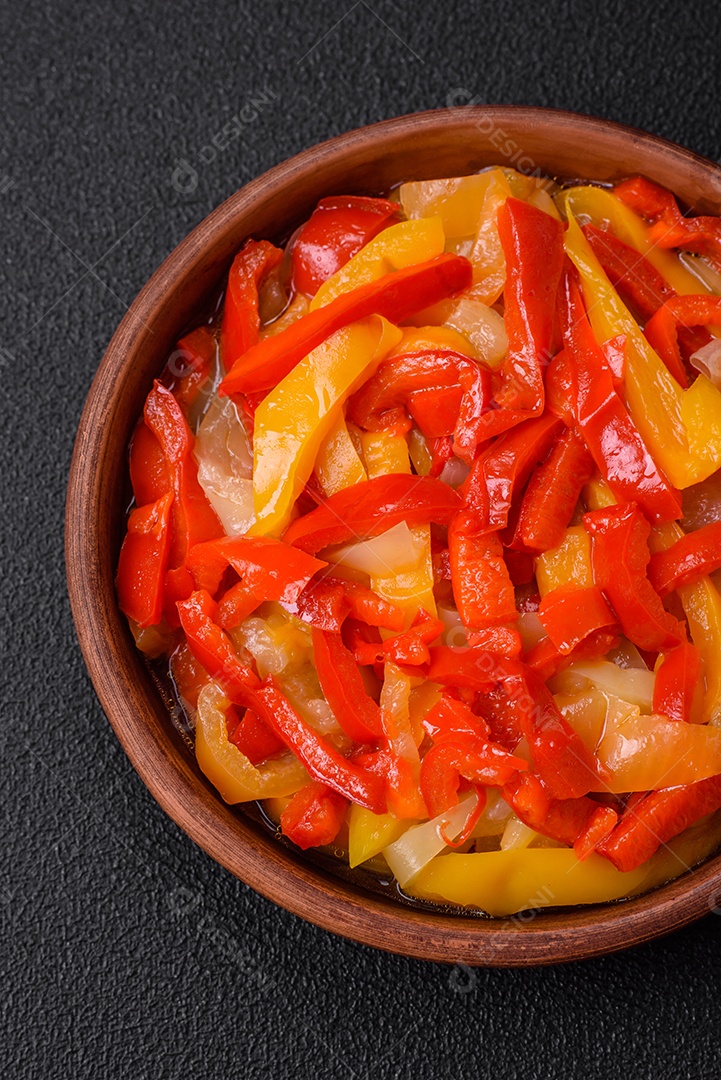 Deliciosas fatias frescas de pimentão doce com cebola, sal, especiarias e ervas sobre um fundo escuro de concreto